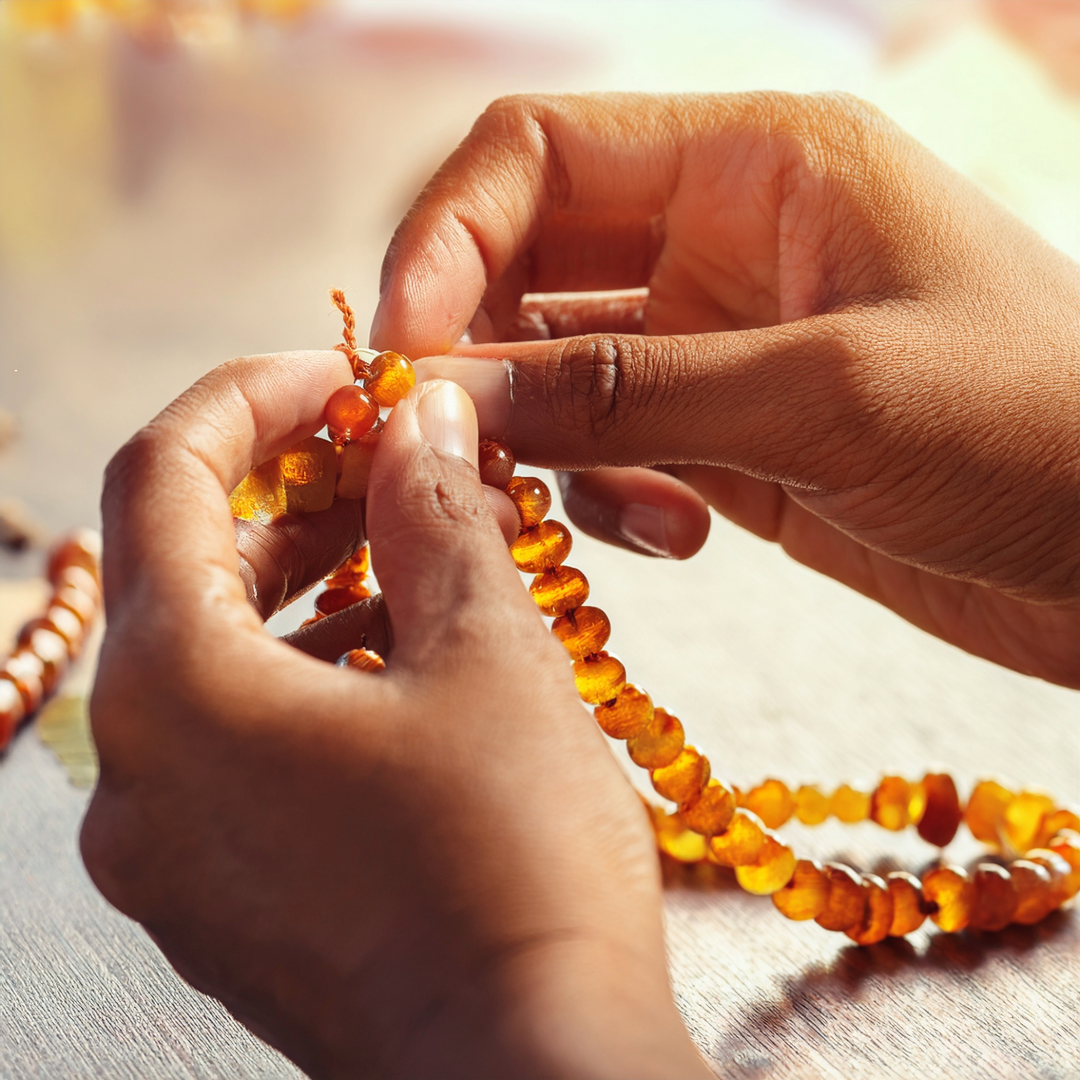 Hands making amber jewellery on table