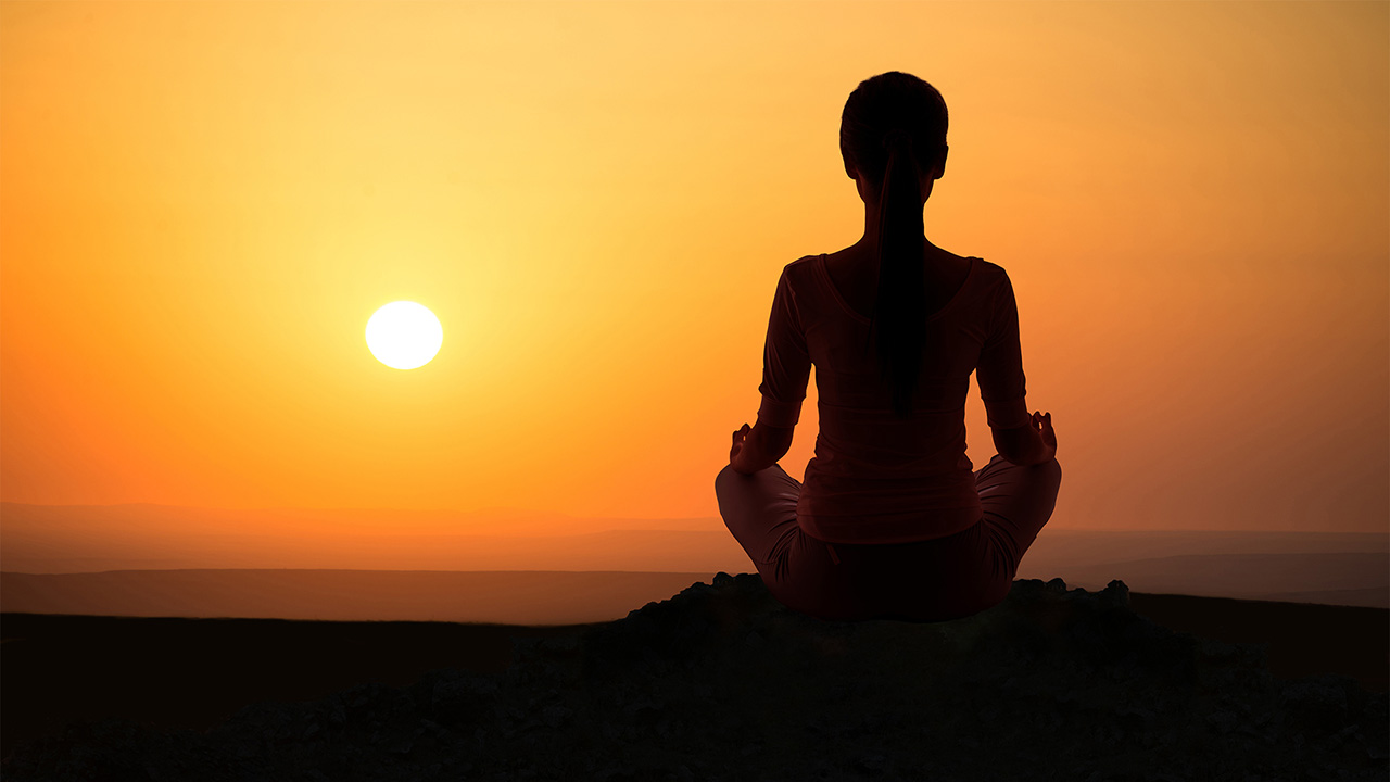 hand on knees meditating at sunset