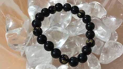 Obsidian bead bracelet resting on Quartz tumbles