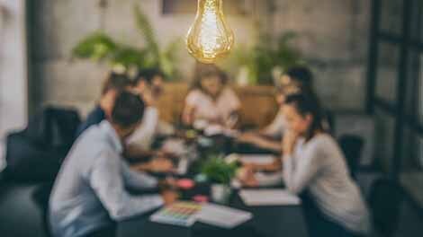 Team of people at table with light bulb in foreground